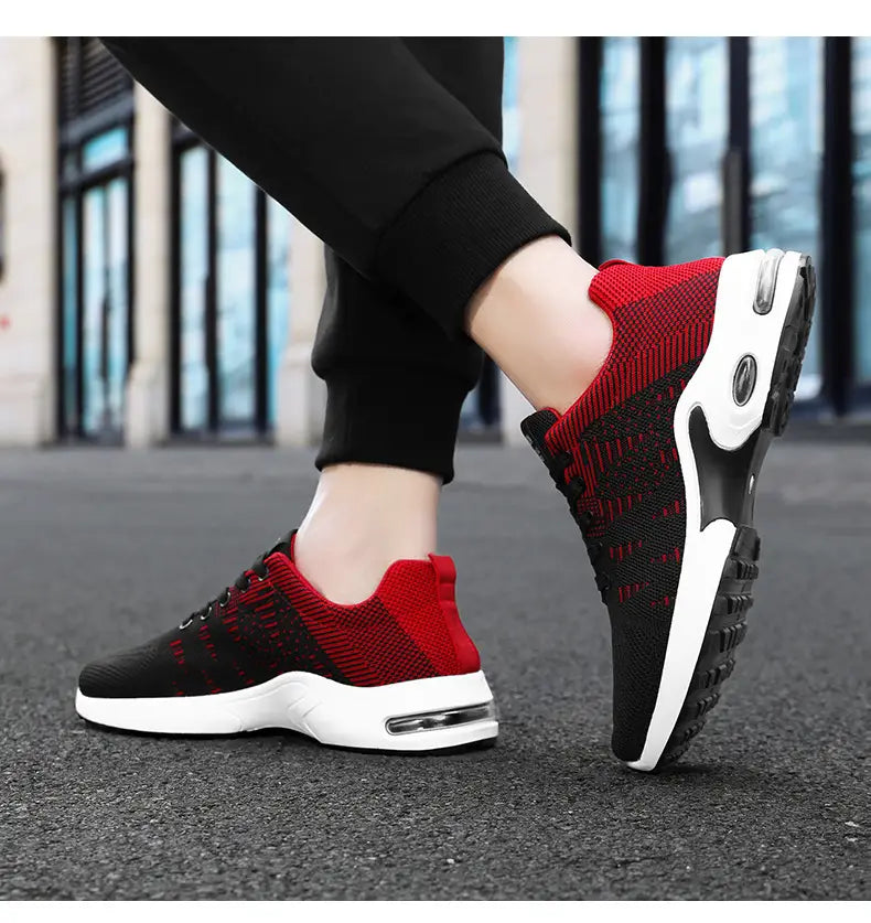 Baskets décontractées pour hommes en mesh flyknit à coussin d’air, en rouge et noir, en tricot, avec des semelles intermédiaires blanches comportant des unités d’amorti par coussin d’air visibles.