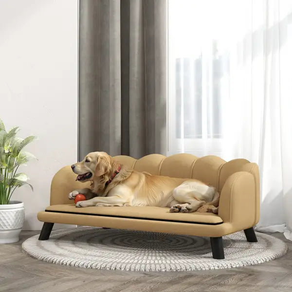 Sofá para mascotas de dos plazas con tapizado beige, bordes ondulados, fabricado en cuero sintético y con patas negras, diseñado para la comodidad de las mascotas.