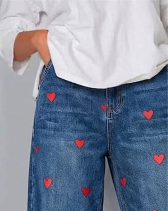 Blue denim jeans for women featuring red heart embroidery on the front.