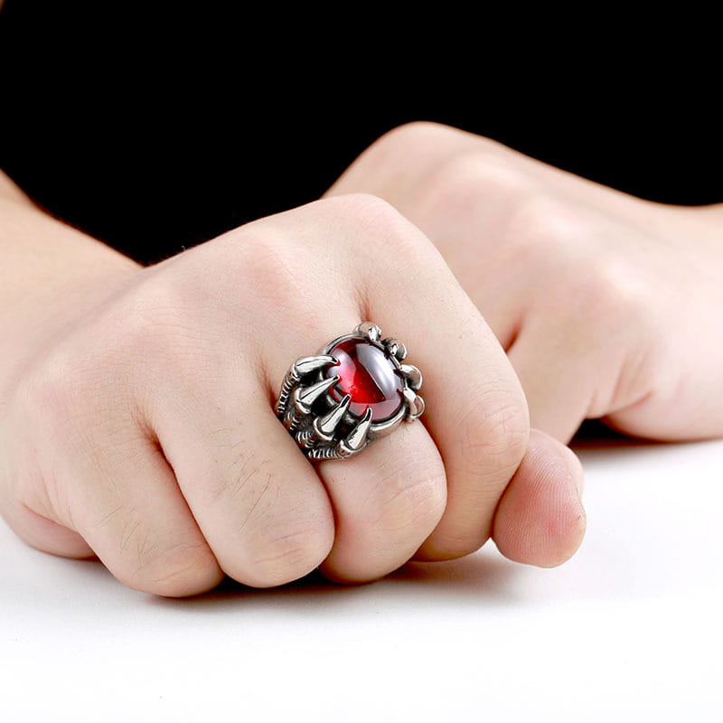 A vintage titanium steel claw ring with a striking silver-toned band and a central red zircon gemstone in an intricate claw-like setting.