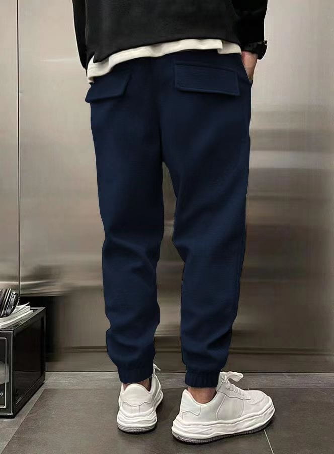 Men’s fleece drawstring sweatpants in navy blue with tapered fit, front pockets, and ribbed cuffs made of soft fleece material.