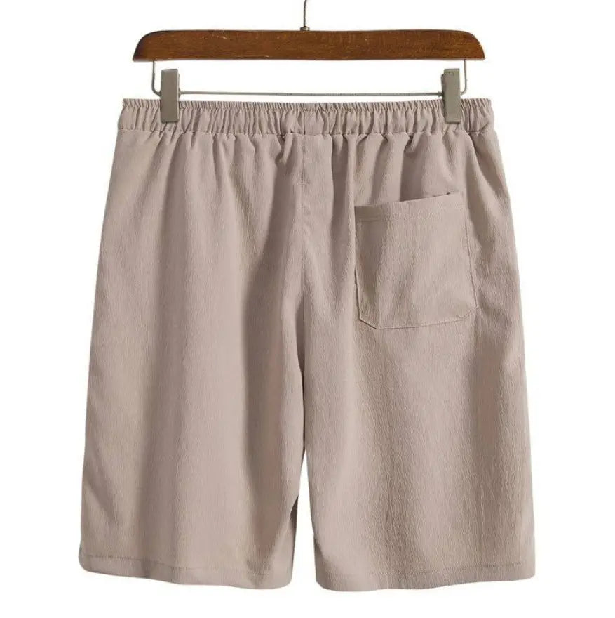 Short de plage en coton lin pour hommes beige présenté de dos, avec une ceinture élastique et une poche arrière unique.