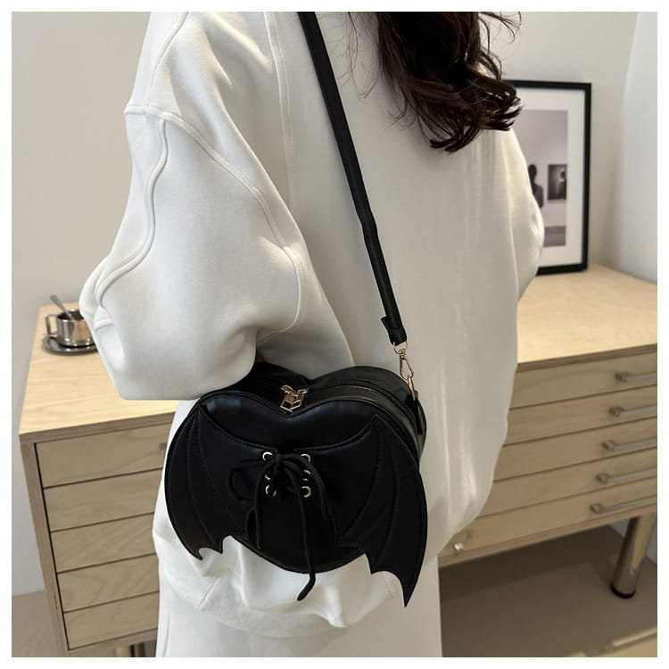 Black bat-shaped crossbody bag with lace-up front detail and metallic clasp suitable for gothic fashion accessories.