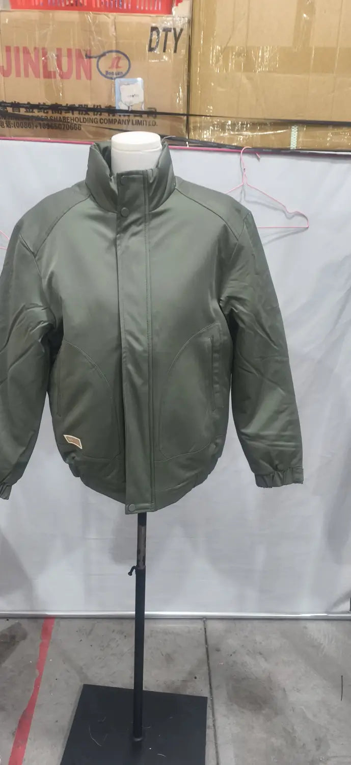 Herren-Steppjacke für Arbeitskleidung in Olivgrün mit gepolstertem Material, hohem Kragen und Reißverschlussverschluss, auf einem Schaufenster-/Mannequin präsentiert.