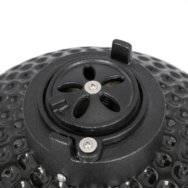 Black cast iron 13 inch ceramic kamado charcoal grill in black with textured honeycomb-patterned surface and circular vent cover featuring five leaf-shaped openings.