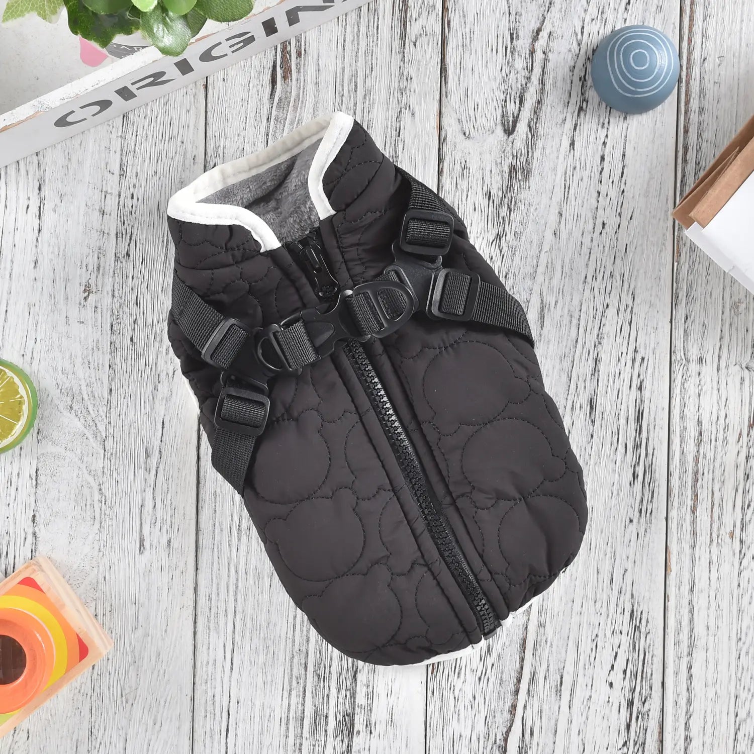 Black quilted dog vest with white trim and adjustable black straps designed as a windproof warm pet coat.