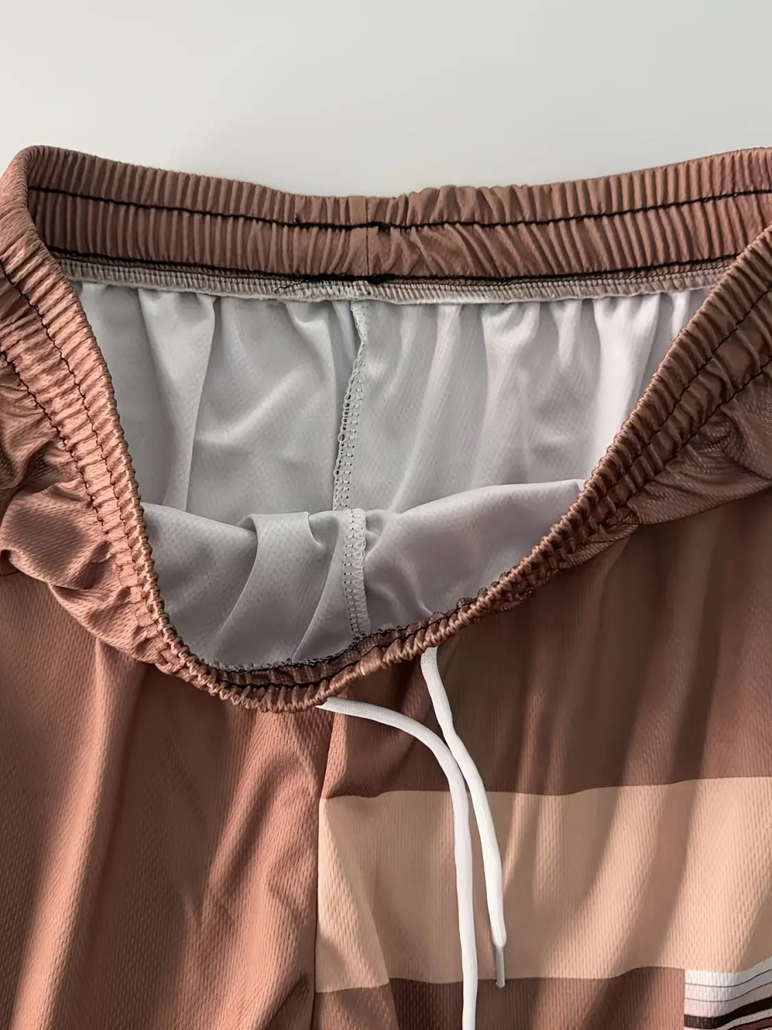 men striped athletic short set featuring brown and beige ribbed elastic waistband shorts with white drawstrings and light gray interior lining