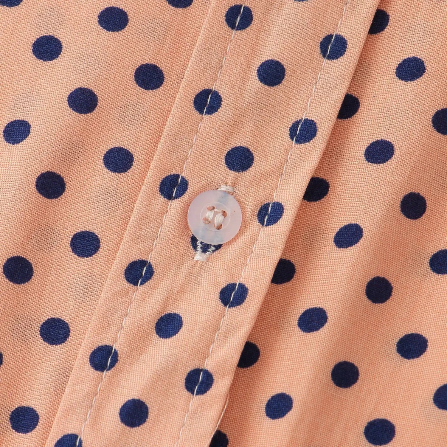 a translucent white button with a subtle pattern on a men plus size peach polka dot floral button up shirt fabric