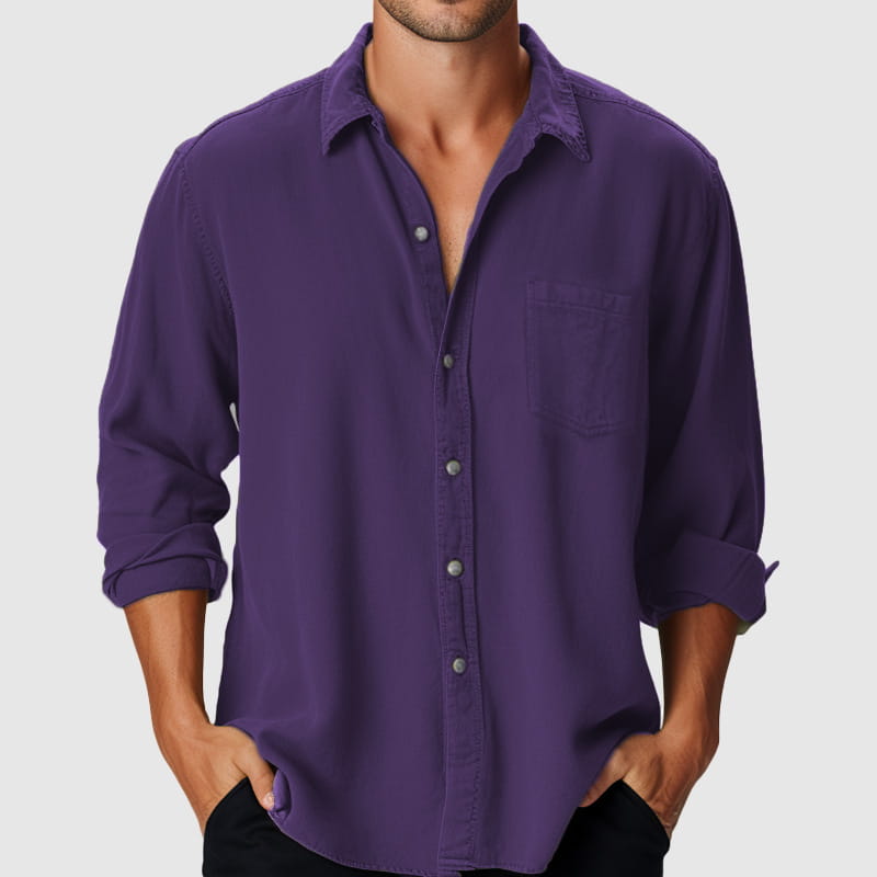 Herren-Longsleeve-Freizeithemd am Strand in einfarbigem tiefem Violett mit umgekrempelten Bündchen und einer Brusttasche aus leichtem, atmungsaktivem Stoff.