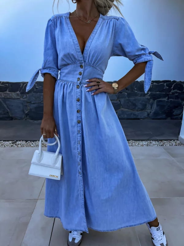Light blue denim midi dress with v-neck button-front closure and tied cuffs featuring puff sleeves.