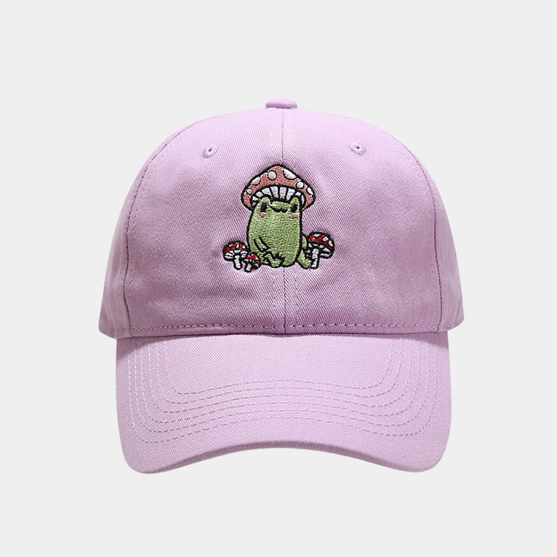 A soft lavender baseball cap featuring a charming embroidered design of a green frog sitting under red and white mushrooms.