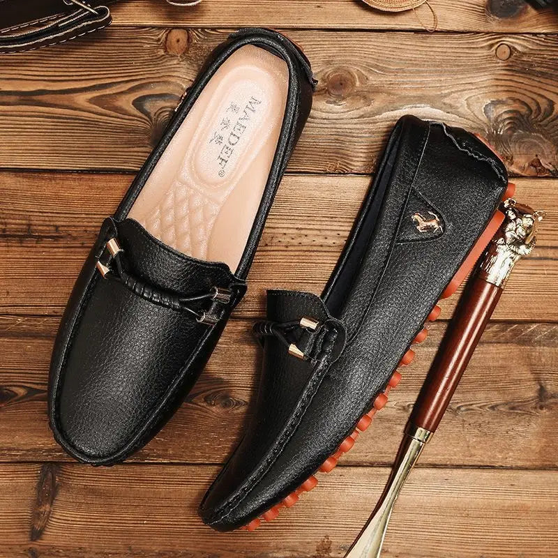 Men’s plus size black leather driving moccasin loafers with a textured surface gold-tone metal accents on the front strap and orange rubber soles.