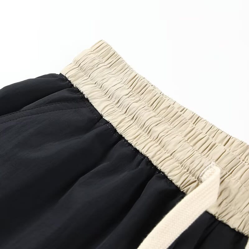 Shorts en nylon décontractés pour hommes, coupe droite, noirs, avec une ceinture élastique beige et un cordon de serrage assorti.