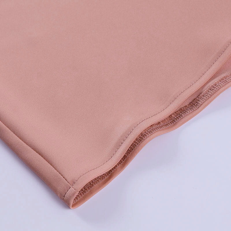 A soft peach-colored satin halter mini party dress fabric with a smooth glossy finish and neatly stitched edges.