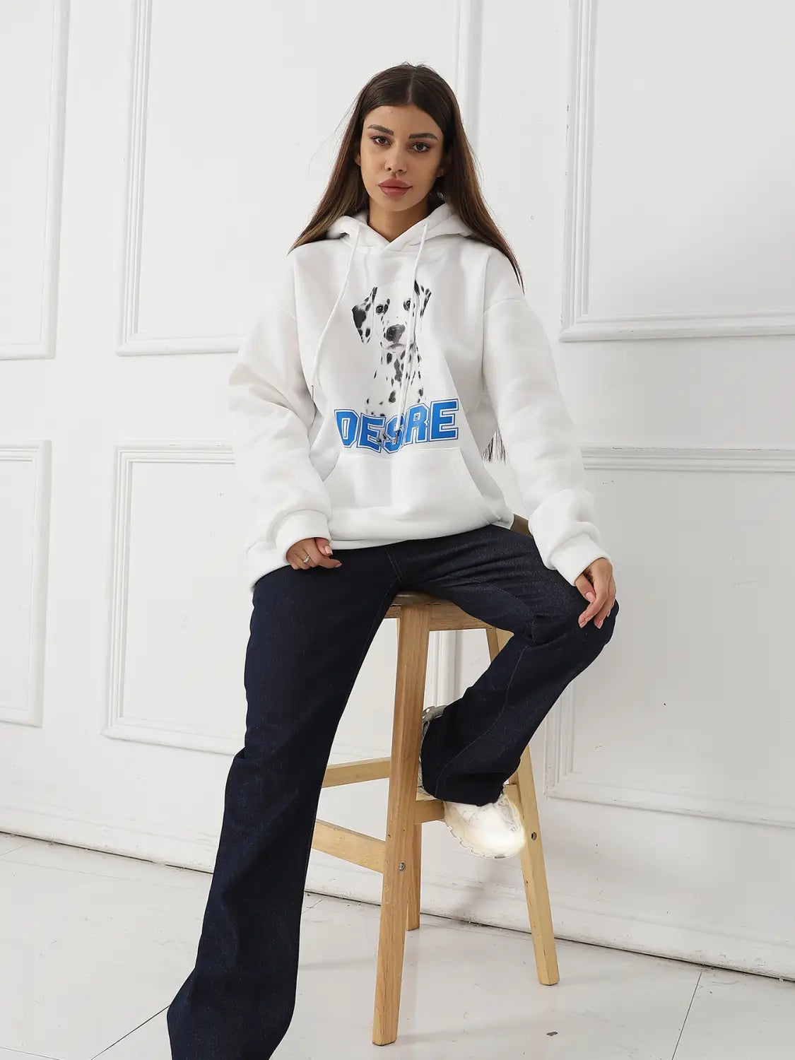 Woman’s white hoodie featuring a black and white dalmatian graphic and blue deare lettering with a cat ear hood.