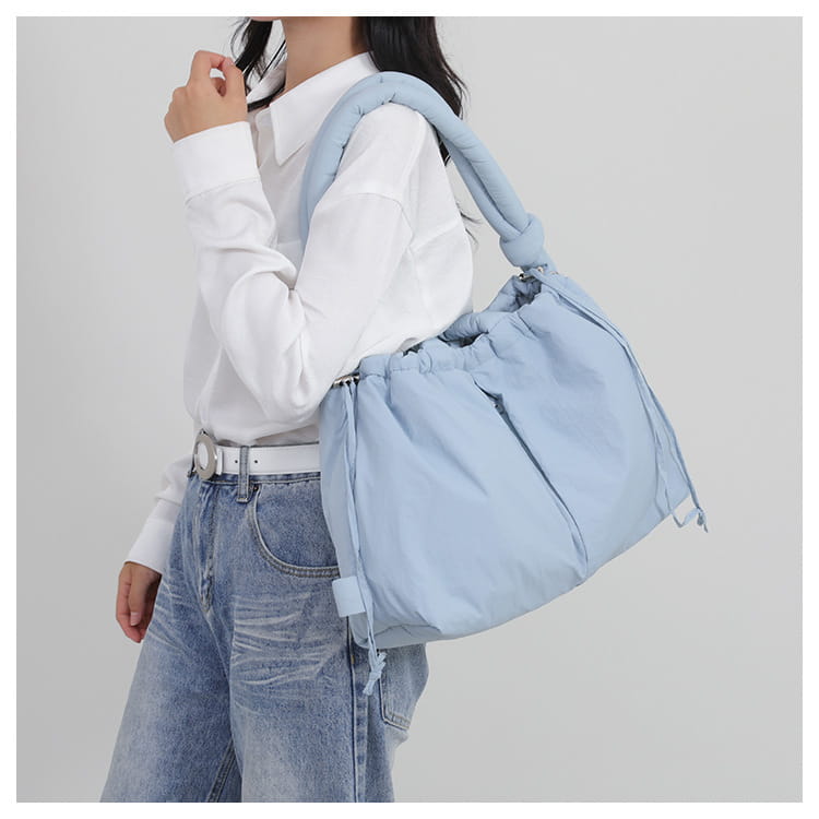Light blue lightweight nylon shoulder bag with quilted puffer design, puffy shoulder strap, and drawstring closure.