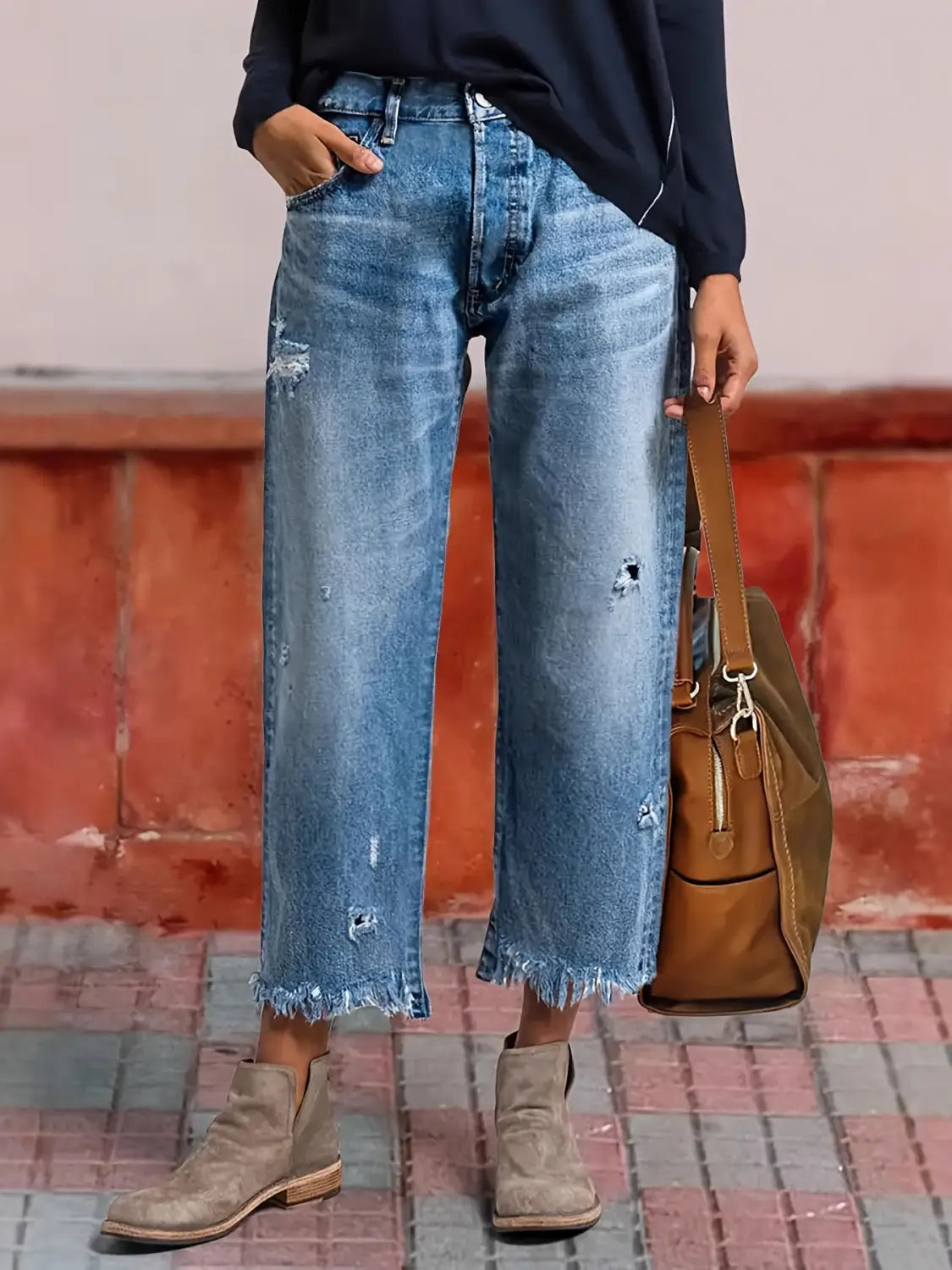 Jeans droits gris délavé déchirés confectionnés dans un denim bleu, avec une coupe courte et évasée (jambe large) et des ourlets effilochés.