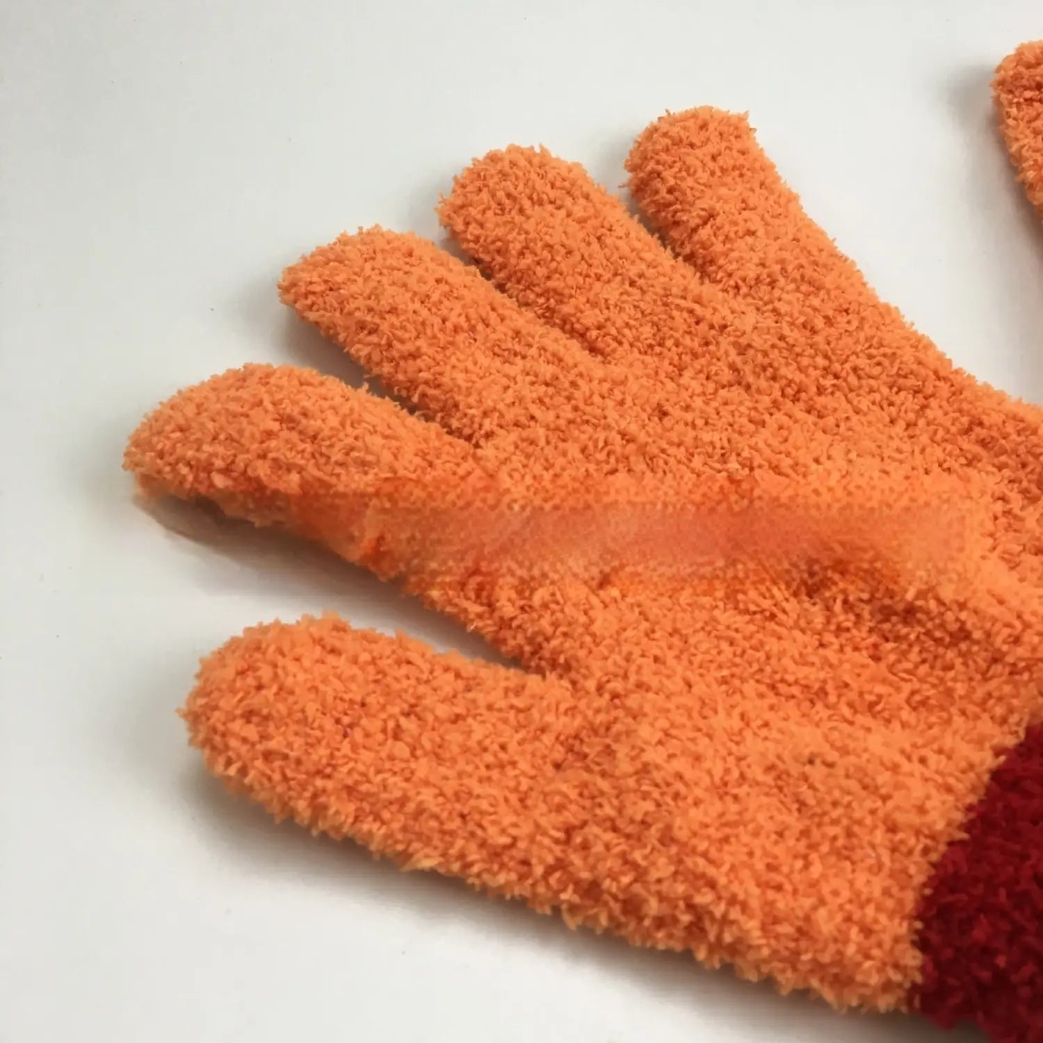 Plush coral fleece bath dust glove in orange with a soft texture and red cuff for effective cleaning.