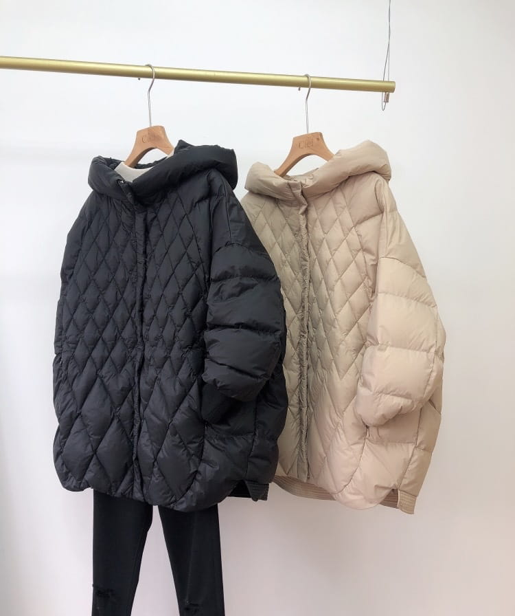 black and beige quilted hooded white duck down puffer jackets hanging on wooden hangers designed for loose fit winter use