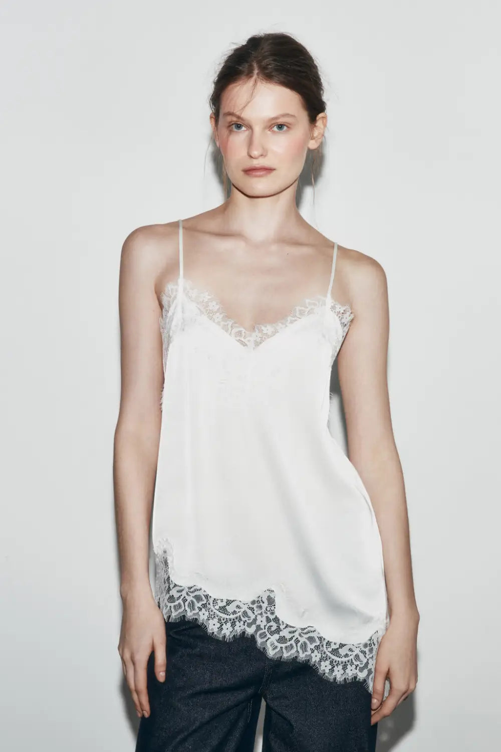Weißes Satin-Camisole-Top mit zartem braunem Spitzenbesatz entlang des Ausschnitts und Saums