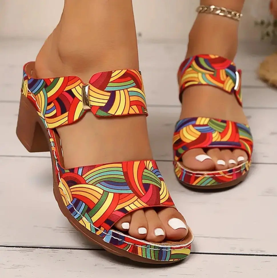 Colorful rainbow-patterned graffiti high heel slide sandals with an open toe, chunky heel, and metallic buckle.