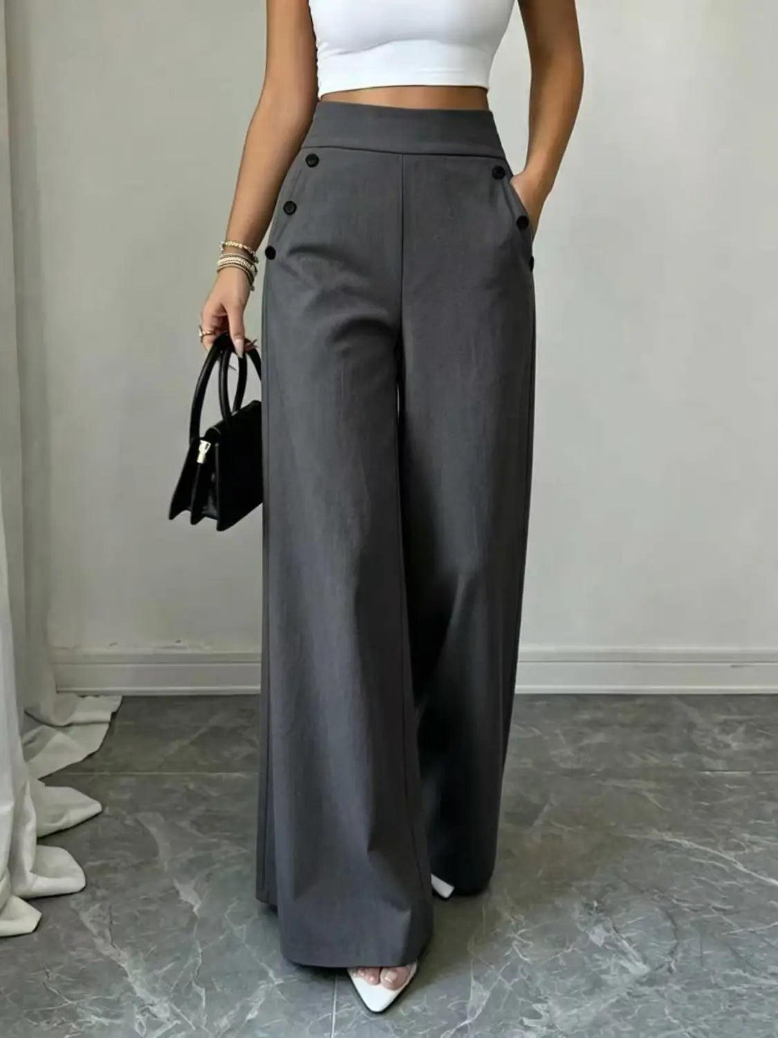 Pantalon ample taille haute en tissu gris avec accents de boutons noirs, pour une tenue élégante et confortable.