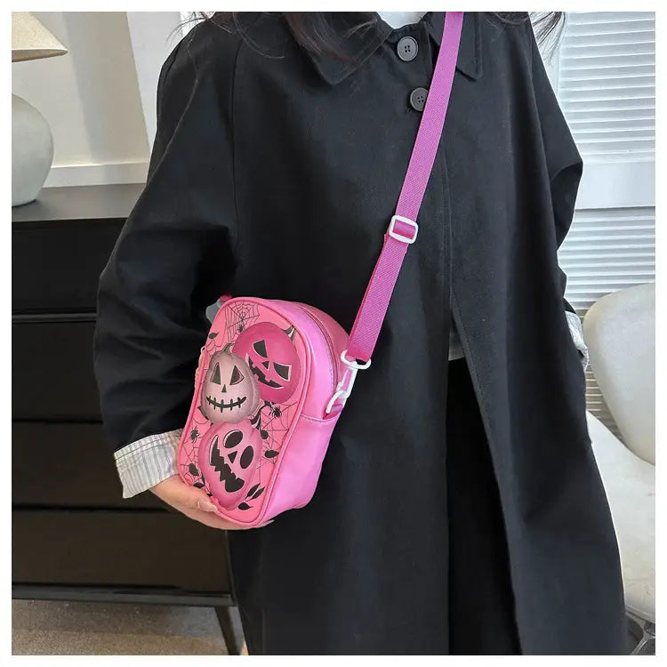 Pink embroidered halloween floral and pumpkin crossbody bag featuring jack-o-lantern designs and a matching pink strap for festive seasonal use.
