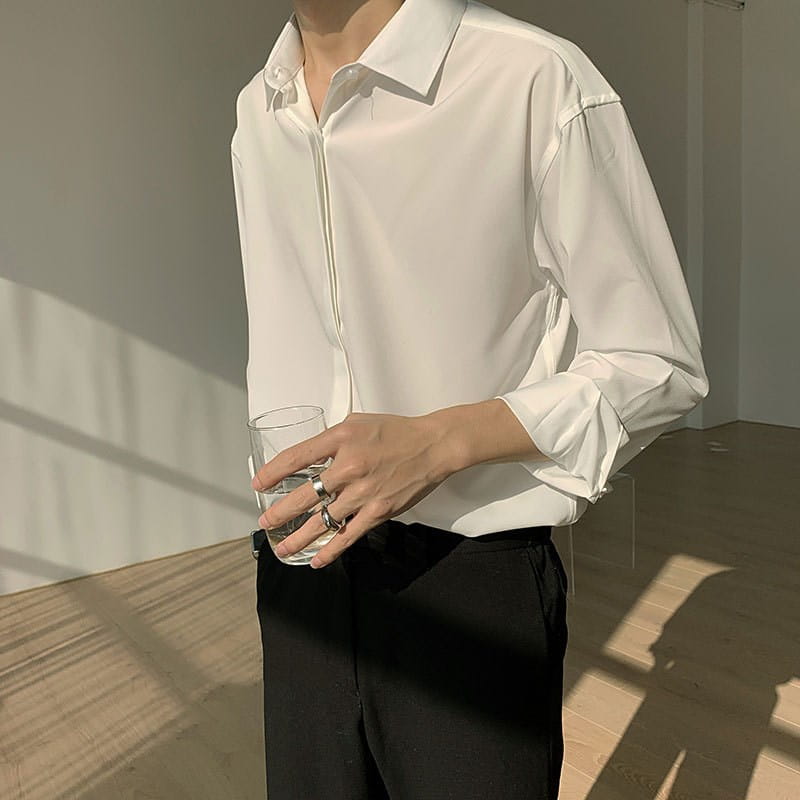 A crisp white retro drape wrinkle resistant satin button down shirt with long sleeves, a classic collar, and subtle pleats at the cuffs.