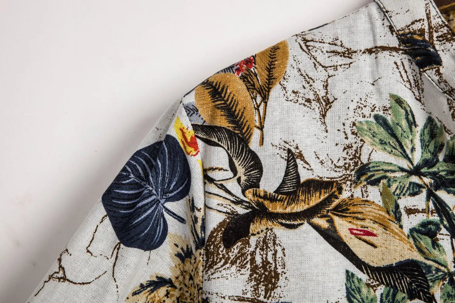 A white slim fit men’s short sleeve button shirt with a vibrant tropical floral print in green brown navy blue and yellow.