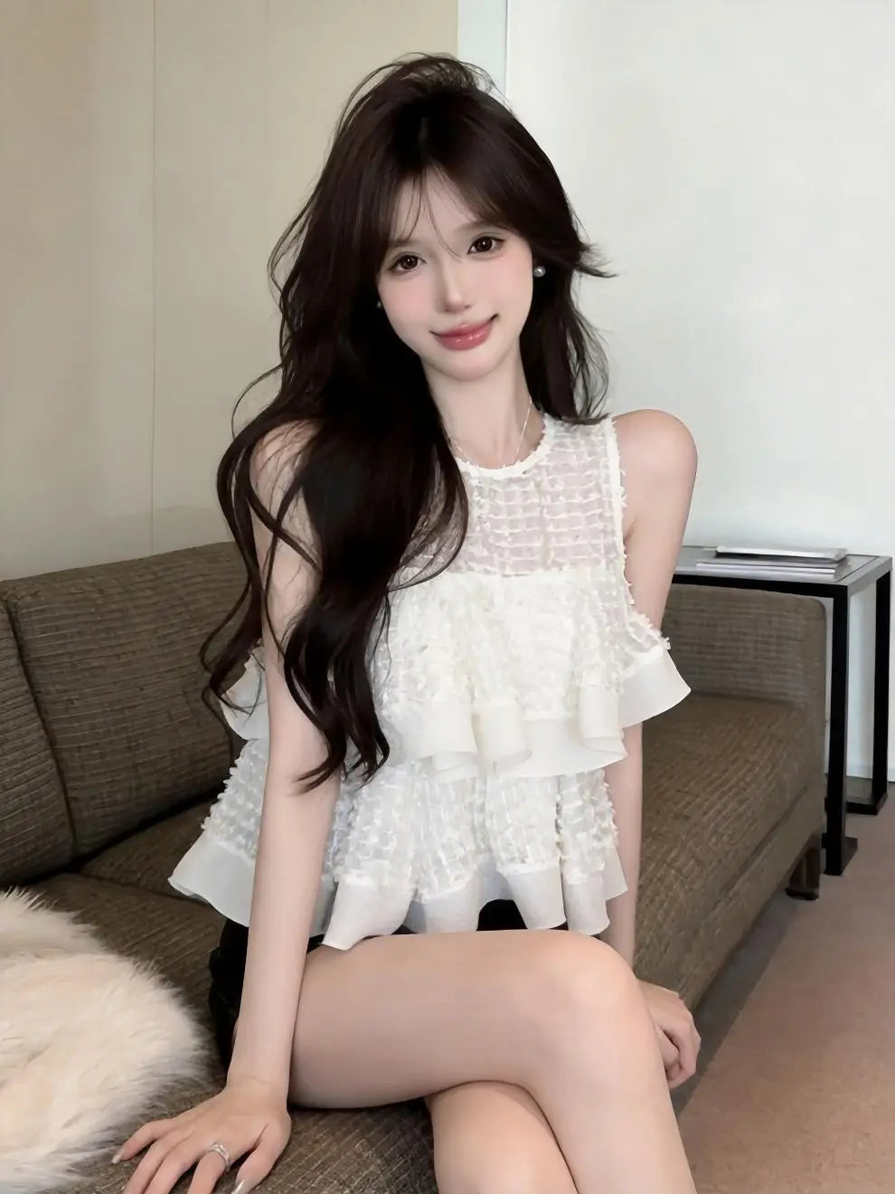 Blusa blanca sin mangas con volantes en capas y cuerpo de malla translúcida que muestra un delicado diseño de volante.