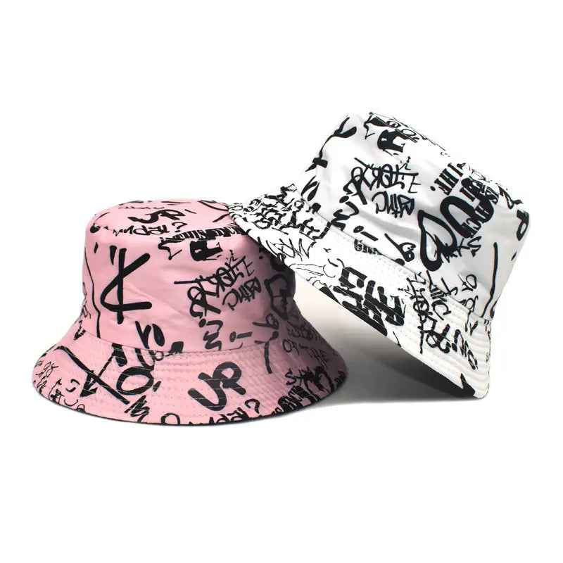 Chapeaux bob graffiti rose et blanc avec lettrage style graffiti noir, conçus comme des chapeaux de voyage respirants avec protection solaire.