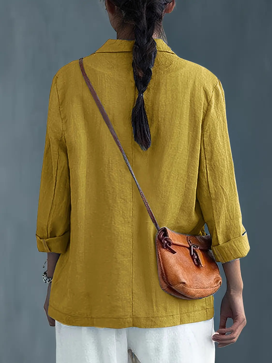 Un bolso cruzado de cuero color camel con cierre de hebilla y correa ajustable, complementa el blazer de lino para mujer, casual y de trabajo.