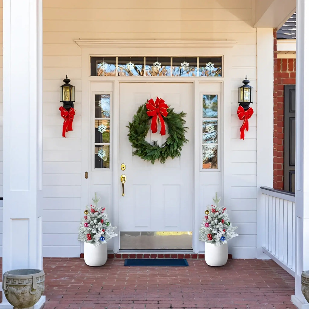 A festive green wreath with a red bow hanging on a white door alongside a 50 led pre-lit mini artificial christmas tree with timer