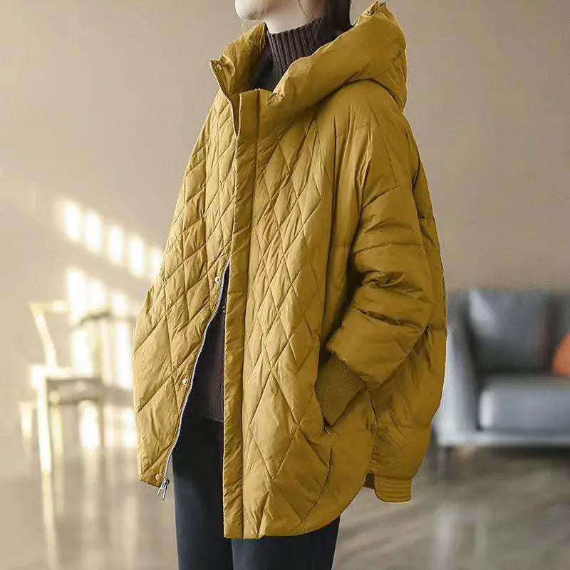 Mustard yellow quilted hooded white duck down puffer jacket designed as a loose winter coat.
