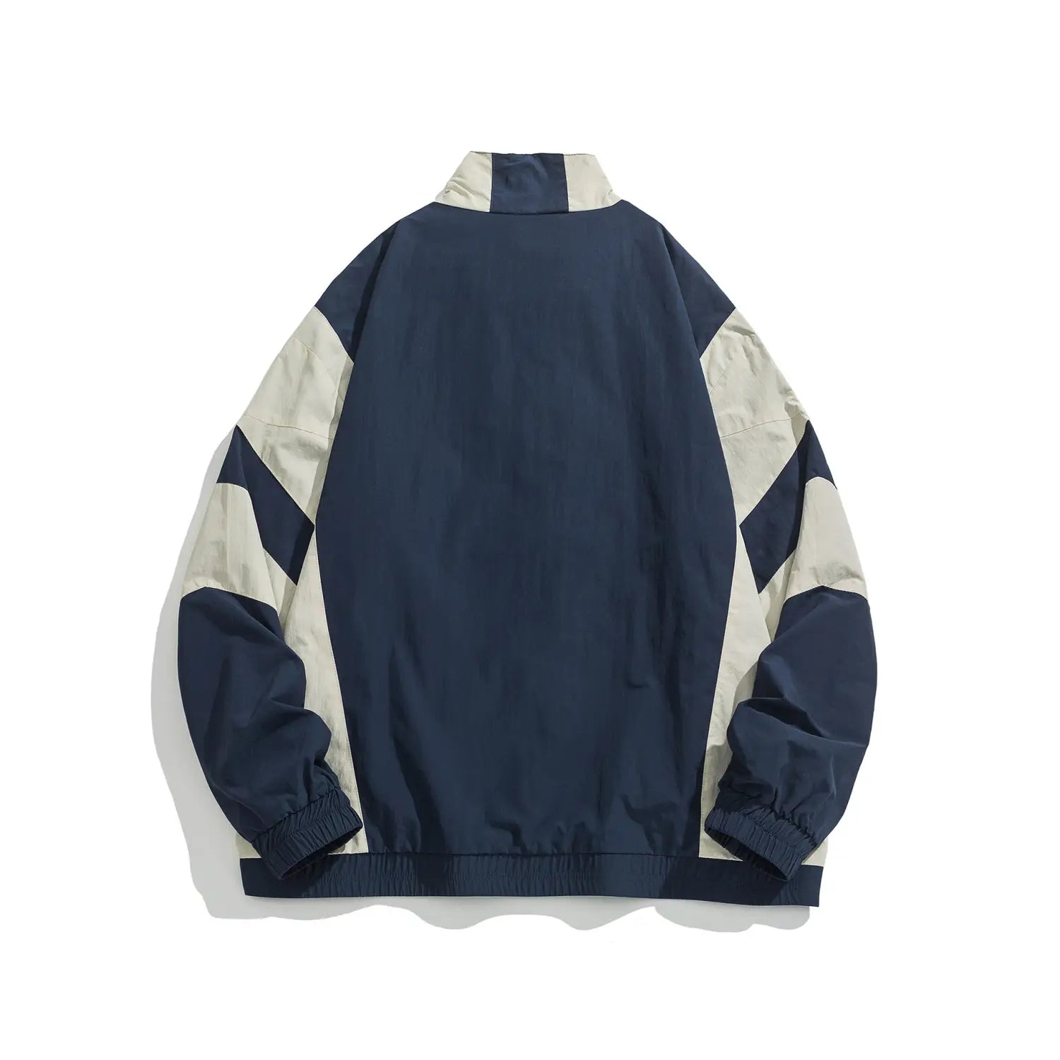 Veste coupe-vent ample bleu marine et crème à blocs de couleurs brodés, avec un empiècement en panneaux diagonaux sur les manches.