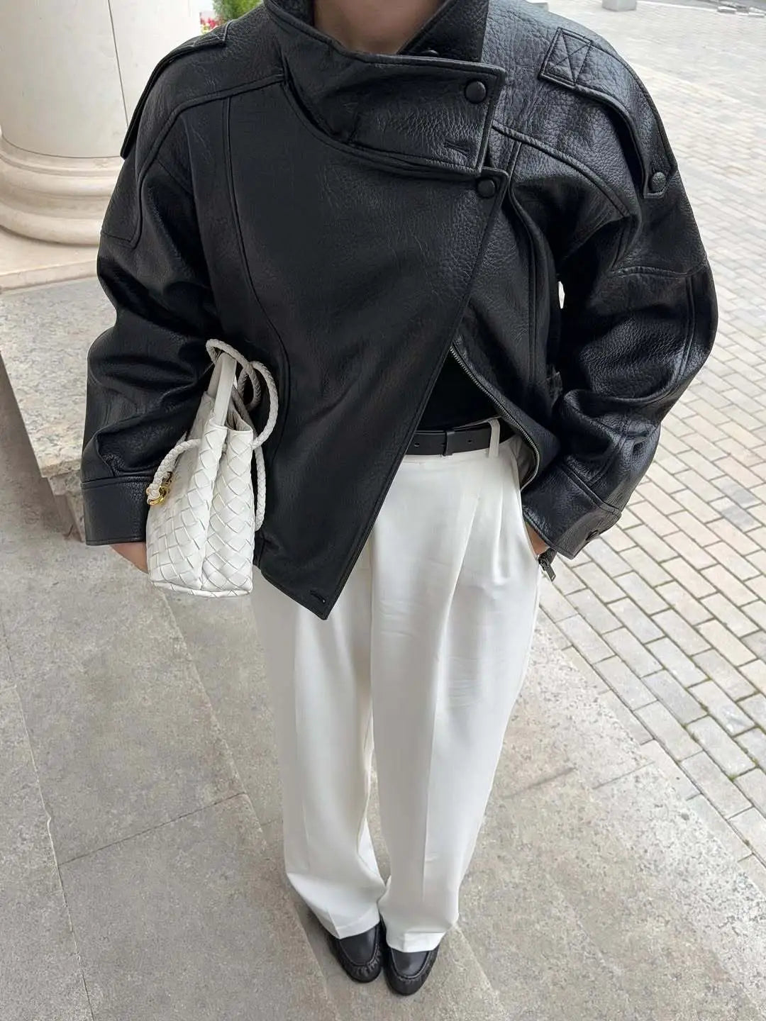 schwarze Damen-Motorradjacke mit hohem Stehkragen aus Kunstleder mit asymmetrischer Front und Knopfdetails.