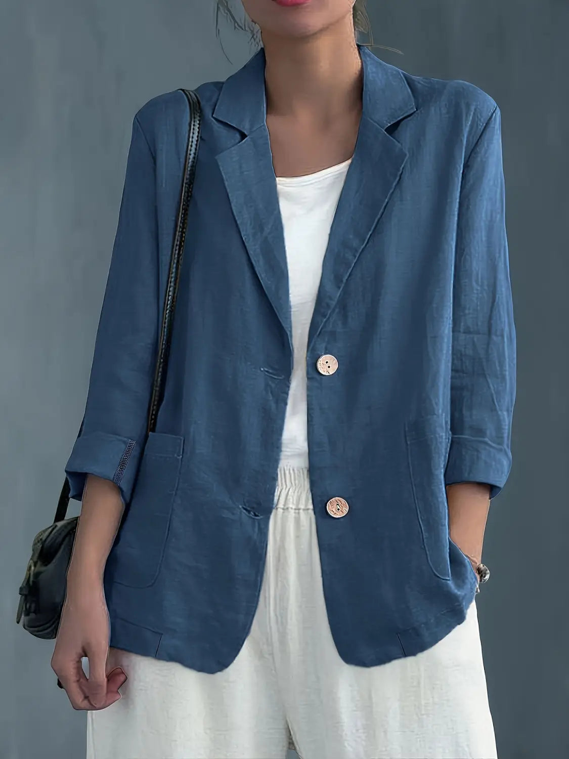 Blazer de lino azul con botones rosa claro, diseñado como chaqueta de trabajo casual para mujer.