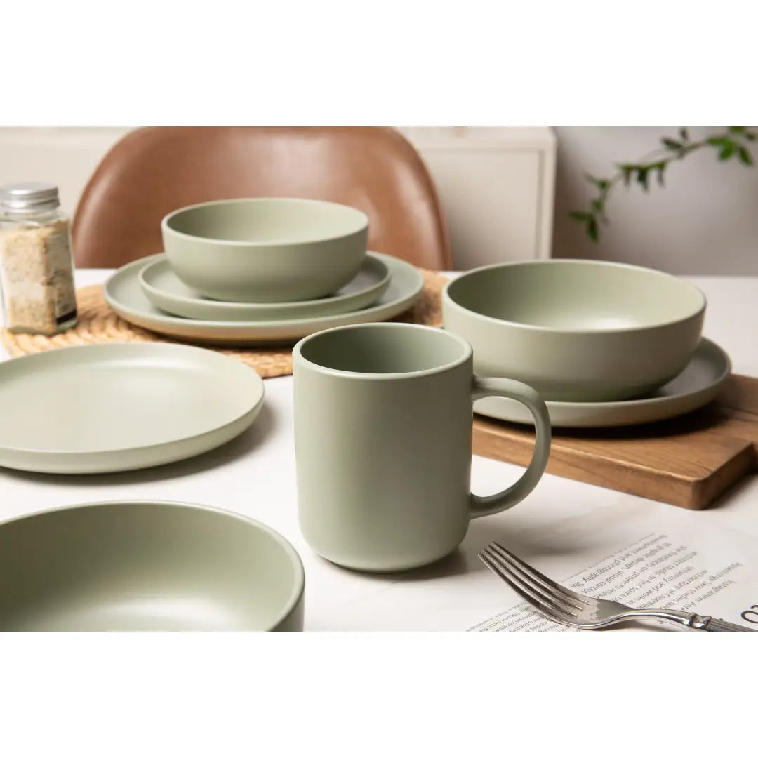 tasse en grès cérame vert sauge atténué, finition mate lisse et anse cylindrique simple, issue d’un ensemble de vaisselle en grès cérame vert sauge de 12 pièces pour trois personnes.