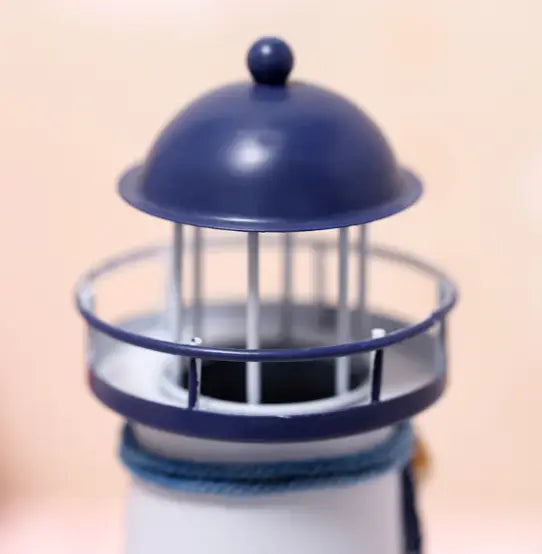 Mediterranean lighthouse garden statue decor featuring a navy blue and white miniature lighthouse model with a domed top, metal railing, and textured base.