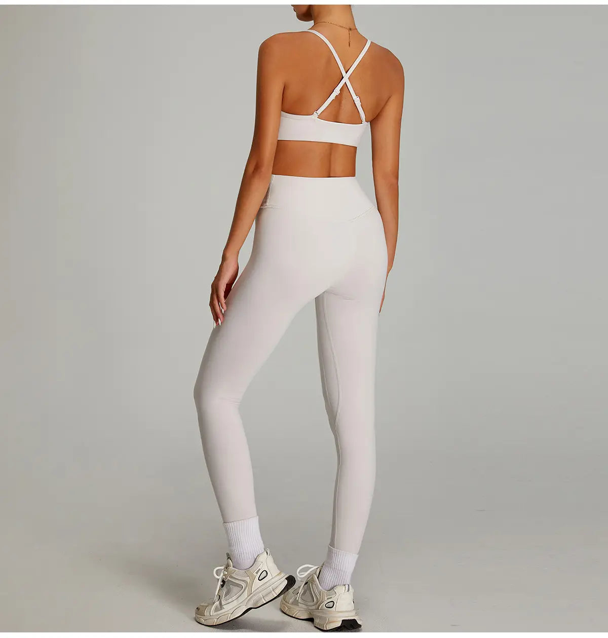 Leggings de fitness blancs taille haute sans couture, avec un tissu à séchage rapide effet nu, assortis à un soutien-gorge de sport blanc présentant des bretelles croisées dans le dos, présenté côté dos.