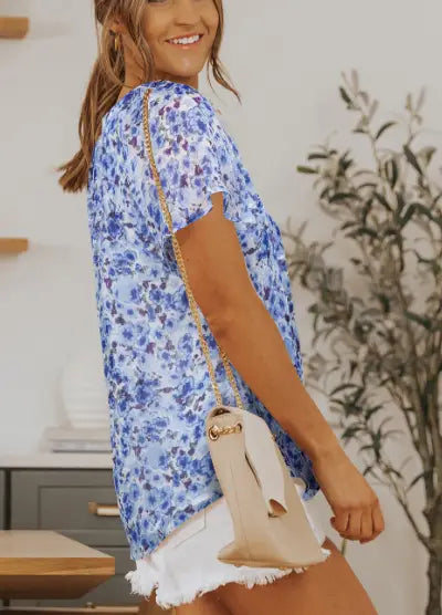 A light blue floral print floral flutter sleeve v neck summer blouse with short sleeves and a relaxed fit.