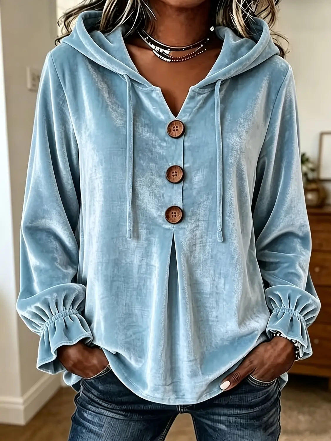 Sudadera de terciopelo azul claro con tres botones de madera y puños fruncidos, exhibida de frente.