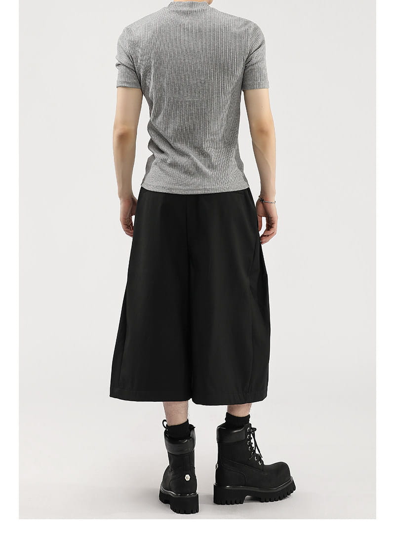 Haut gris à manches courtes côtelées présenté avec un short de costume pour hommes à jambes larges plissées, mettant en avant des détails décontractés et élégants.