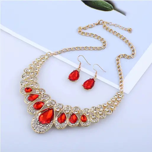 Vintage gold teardrop crystal bridal jewelry set featuring a gold-toned necklace with vibrant red teardrop-shaped stones and clear sparkling crystals in an elegant cascading design.