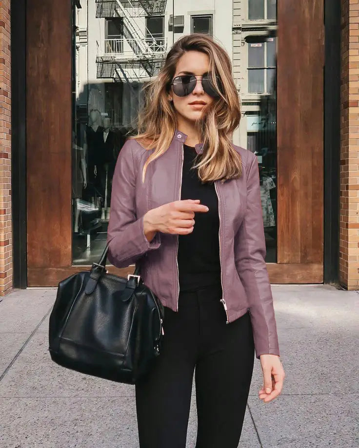 A sleek black leather handbag with a structured shape and top handle complements a women’s faux leather bomber jacket urban casual coat.