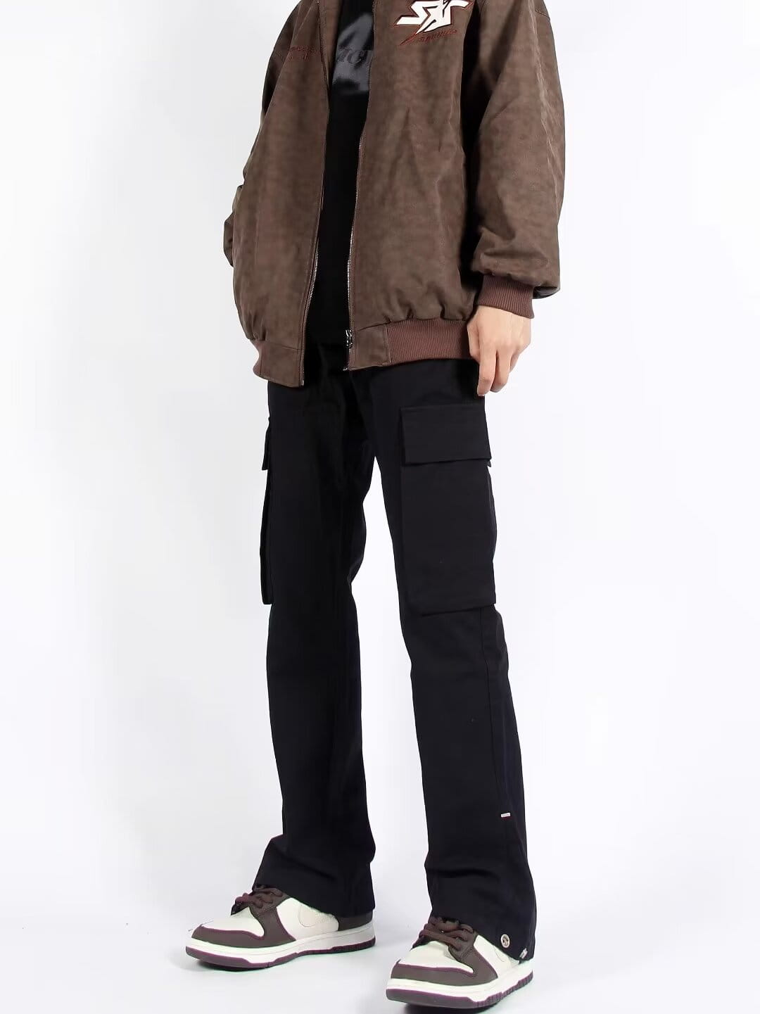 Chaqueta bomber color marrón con logotipo bordado blanco en el pecho, combinada con pantalones cargo rectos de pierna recta con múltiples bolsillos.