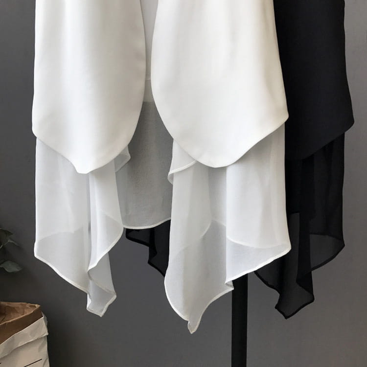 Weiße und schwarze Chiffon-Lagenröcke mit asymmetrischer V-Form aus leichtem Chiffonstoff, auf einem Gestell hängend