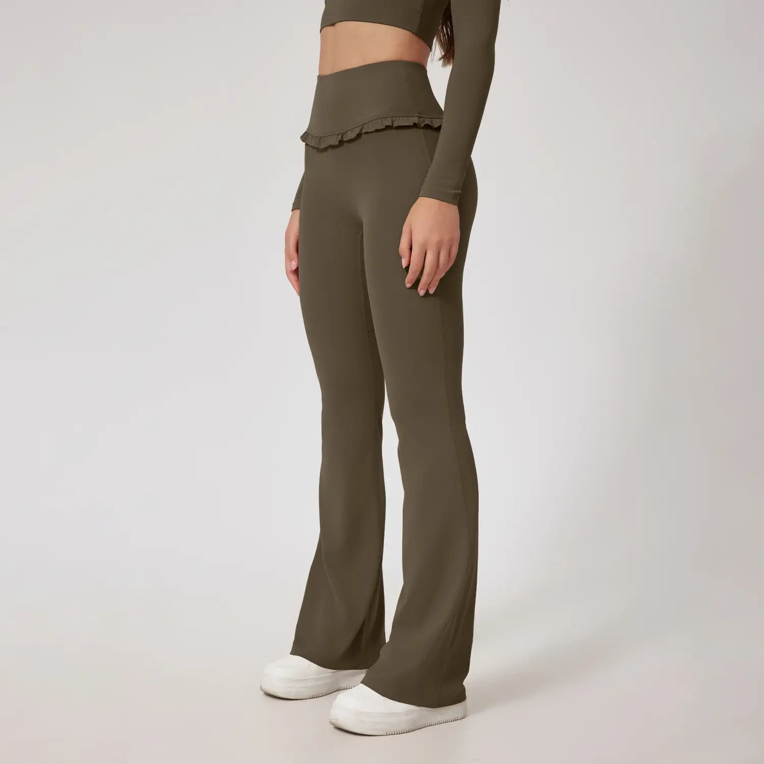 Leggings évasés vert olive taille haute avec une taille à volants, conçus comme pantalons d’activité pour un ajustement confortable et élégant.