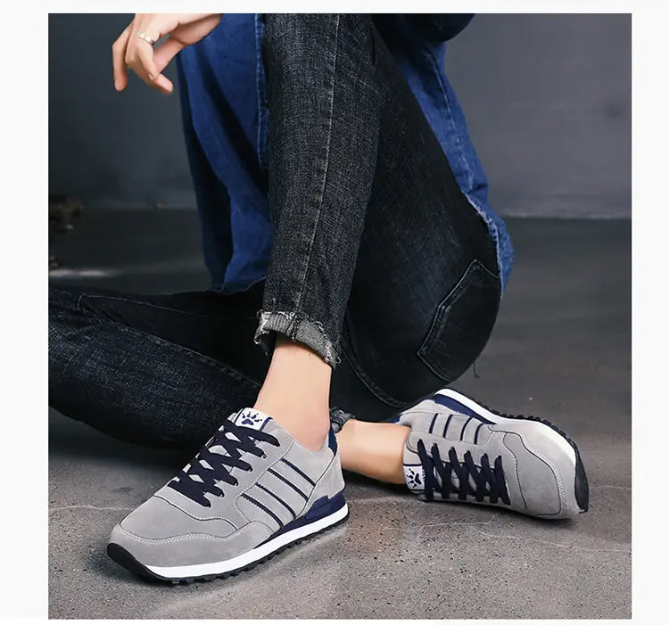 Baskets de mode athlétiques en daim pour hommes en gris et bleu marine, avec dessus en daim, semelle en caoutchouc blanc et trois bandes parallèles sur le côté.