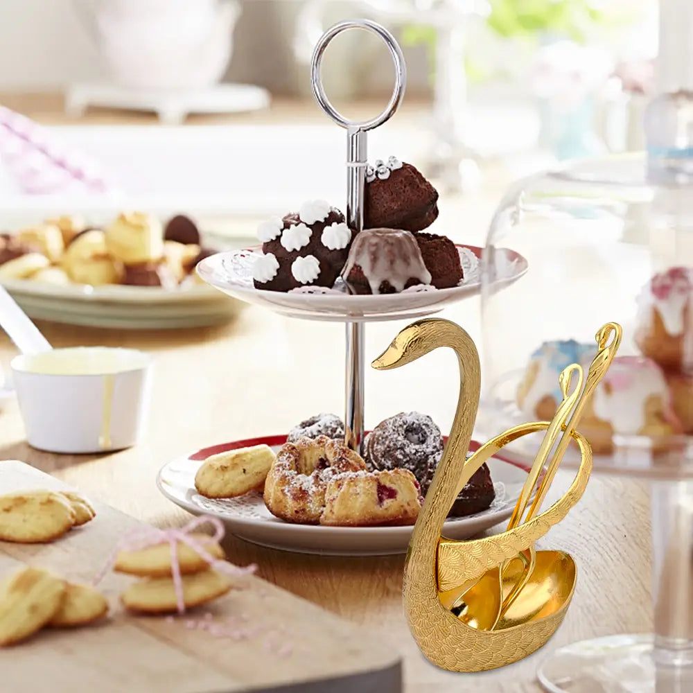 Porte-cuillère à dessert en forme de cygne doré, orné de détails gravés complexes et d’une finition métallique polie, issu du Coffret de coutellerie Cygne en cuillères et fourchettes à dessert dorées.